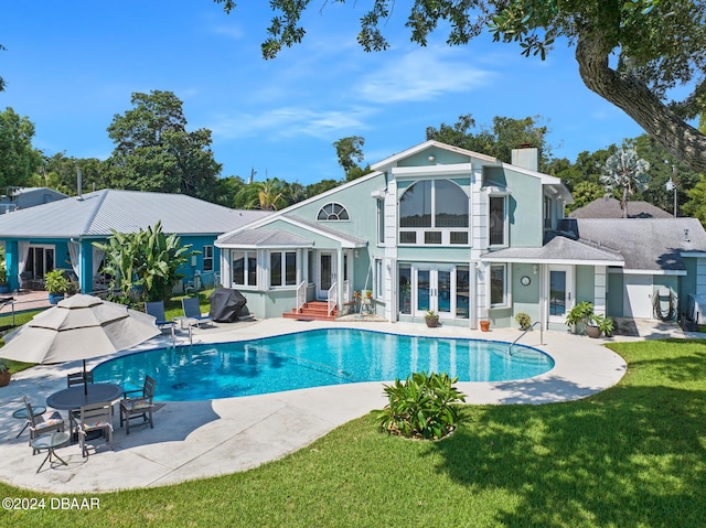 back of property with french doors, a patio, and a lawn