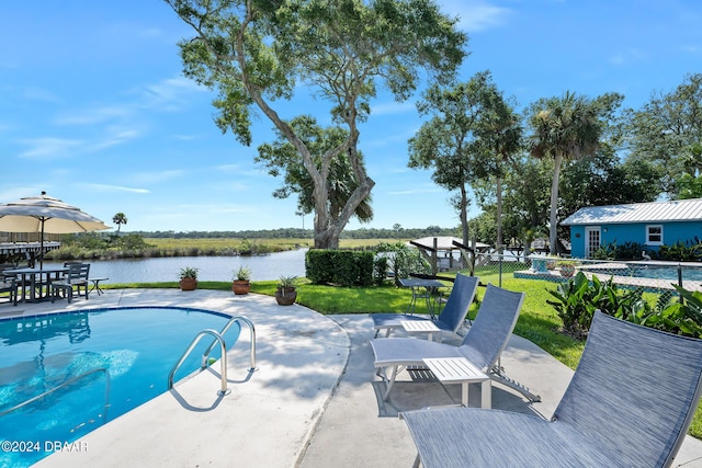 view of pool with a yard, a water view, and a patio