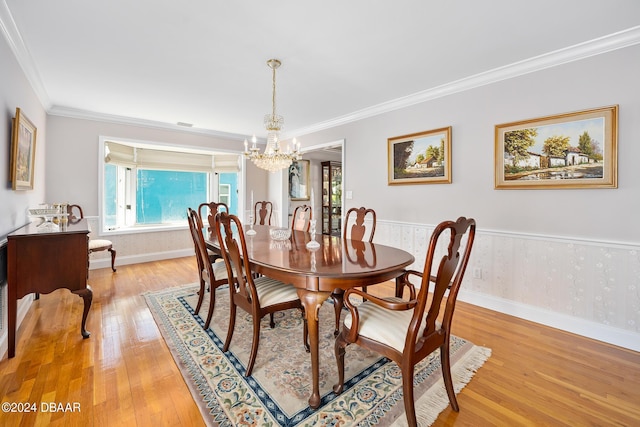 dining room with an inviting chandelier, crown molding, and light hardwood / wood-style flooring