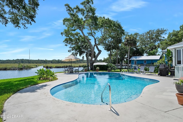 view of swimming pool featuring a patio area, a water view, and grilling area