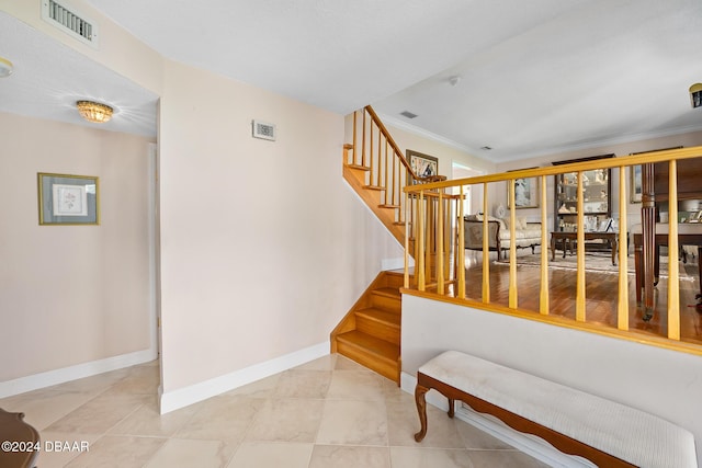 stairs with tile patterned flooring and ornamental molding