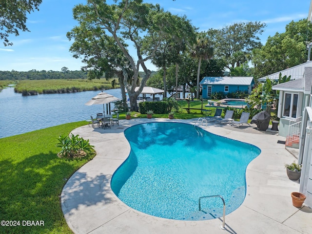 view of swimming pool with a water view, a yard, a patio, and an in ground hot tub