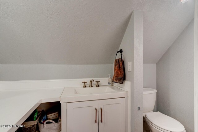 half bath with a textured wall, a textured ceiling, toilet, and vanity