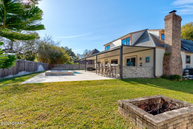 view of yard featuring outdoor dry bar, an in ground hot tub, an outdoor fire pit, and a fenced backyard