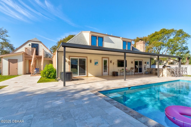 back of house featuring a fenced in pool, an outbuilding, a patio, outdoor dry bar, and area for grilling