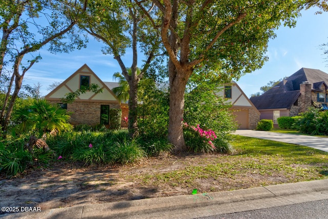 tudor home with a garage, concrete driveway, and brick siding