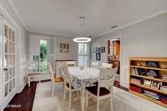 dining room with crown molding, a textured ceiling, visible vents, and wood finished floors