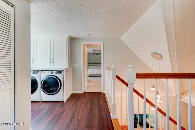 laundry room with dark wood-style floors, a textured ceiling, washing machine and dryer, and cabinet space