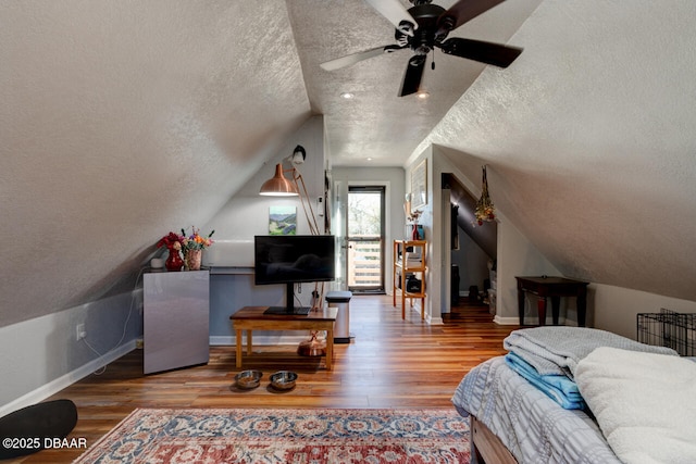 interior space with vaulted ceiling, a textured ceiling, baseboards, and wood finished floors