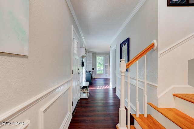 corridor with a wainscoted wall, stairway, wood finished floors, crown molding, and a decorative wall