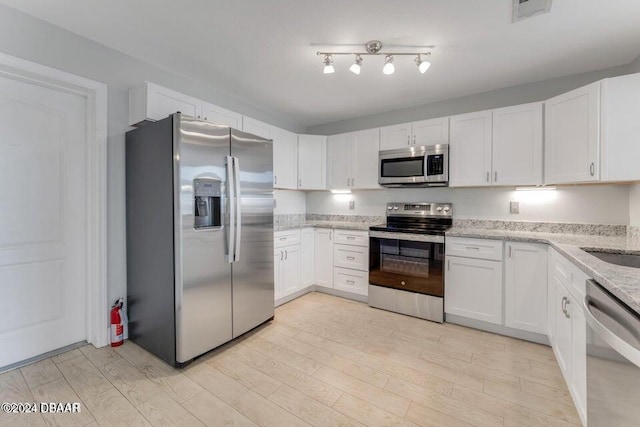 kitchen featuring white cabinets, light hardwood / wood-style floors, light stone countertops, and stainless steel appliances