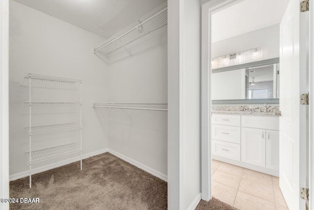 walk in closet with light colored carpet and sink