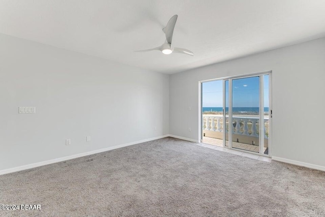 carpeted empty room with a water view and ceiling fan