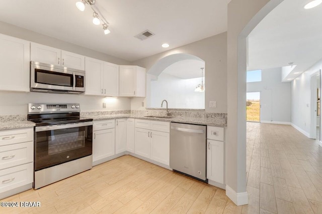 kitchen with light stone counters, sink, white cabinets, and stainless steel appliances