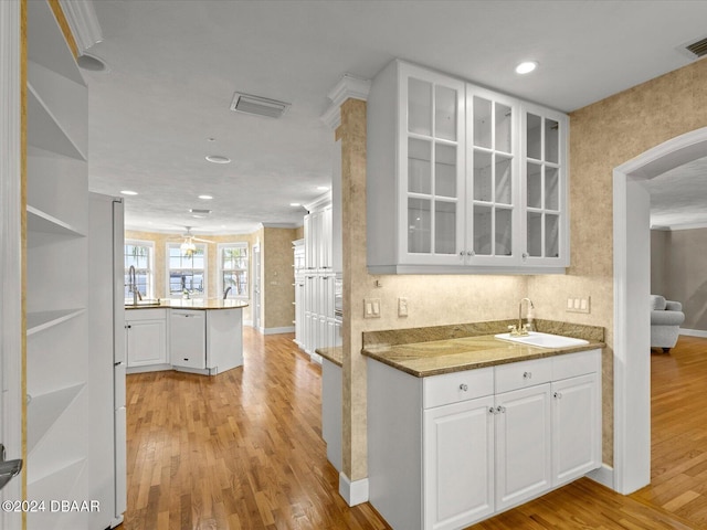 kitchen featuring white cabinets, sink, light hardwood / wood-style flooring, stone countertops, and kitchen peninsula