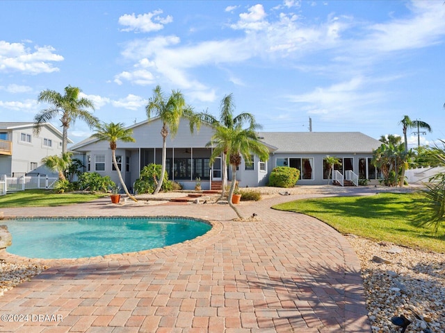 view of pool featuring a lawn, a sunroom, and a patio