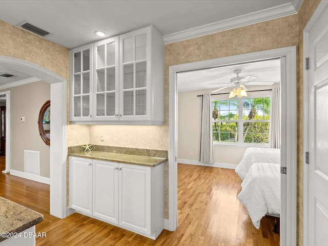 interior space with white cabinets, light hardwood / wood-style flooring, light stone countertops, and ceiling fan