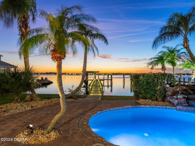 pool at dusk featuring a water view