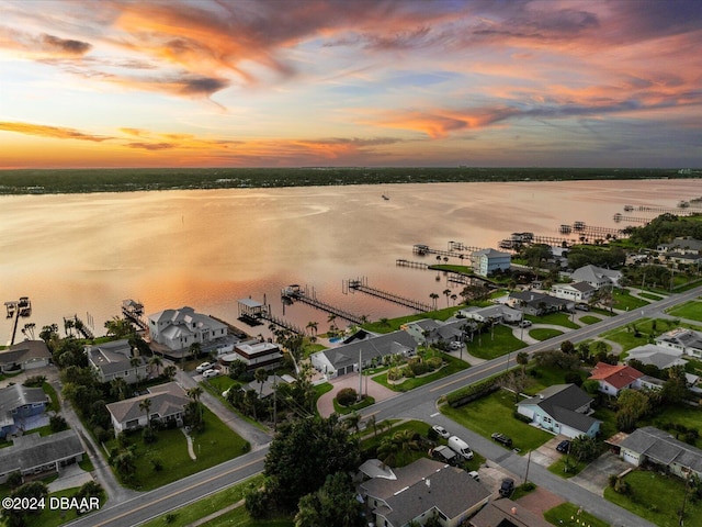 aerial view at dusk featuring a water view