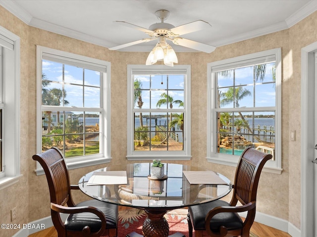 dining area with ceiling fan, crown molding, a water view, and hardwood / wood-style flooring