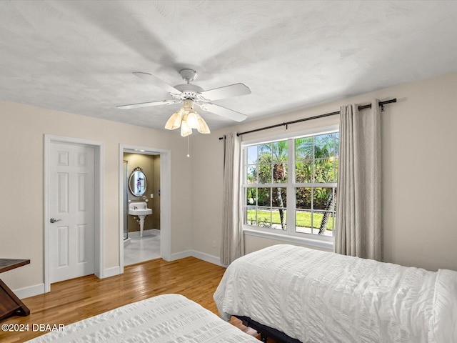 bedroom featuring ceiling fan, ensuite bathroom, and light hardwood / wood-style floors