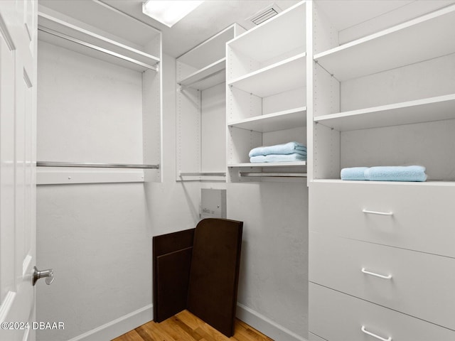 walk in closet with light hardwood / wood-style floors