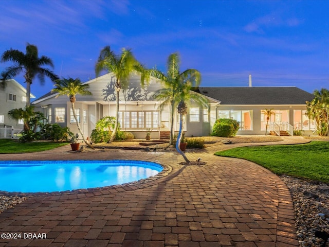 pool at dusk with a patio area