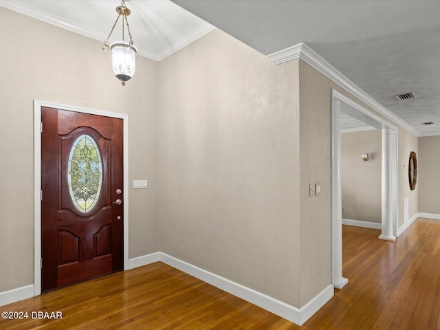 entrance foyer featuring wood-type flooring, ornamental molding, and an inviting chandelier