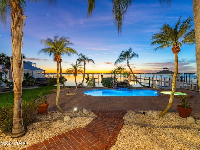 pool at dusk featuring a gazebo, a water view, and a patio area