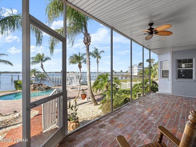 unfurnished sunroom featuring ceiling fan, a water view, and a healthy amount of sunlight