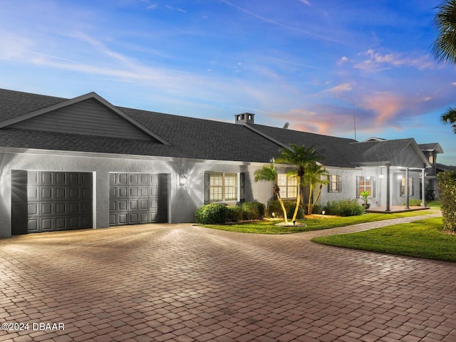 ranch-style house with a garage and a lawn