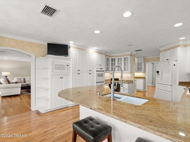 kitchen featuring a kitchen bar, white appliances, sink, white cabinets, and light hardwood / wood-style floors