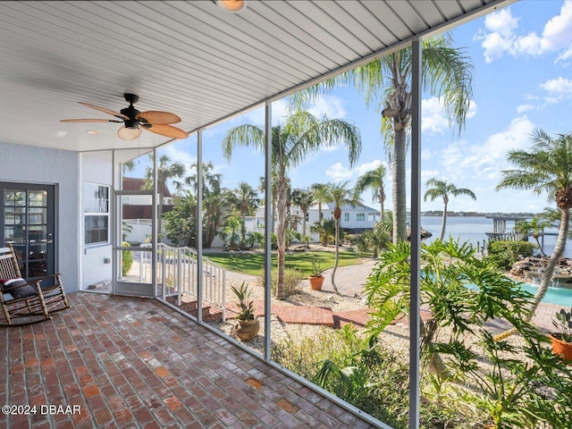 unfurnished sunroom with ceiling fan and a water view