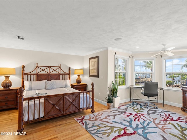 bedroom with ceiling fan, crown molding, a textured ceiling, and light wood-type flooring