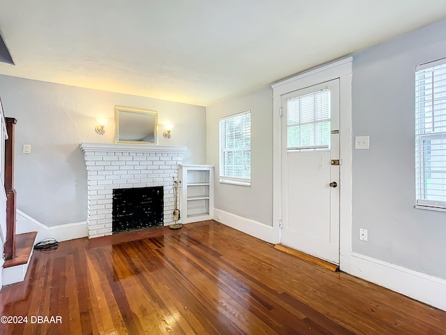 unfurnished living room with hardwood / wood-style floors and a brick fireplace