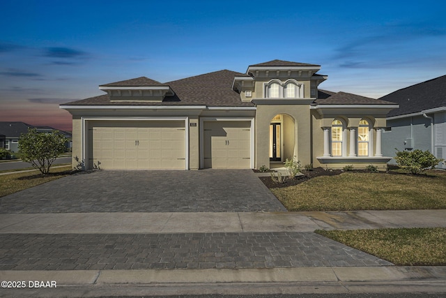 view of front of property with decorative driveway, a garage, roof with shingles, and stucco siding