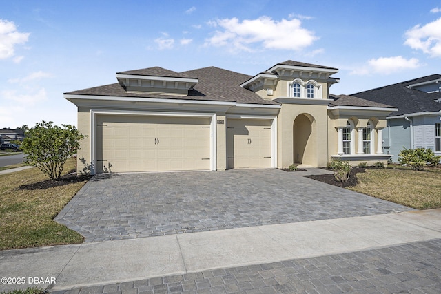 view of front of property with decorative driveway, a garage, and stucco siding