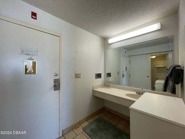 bathroom featuring toilet, vanity, a textured ceiling, and tile patterned floors