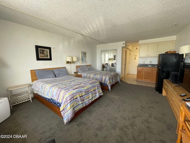 bedroom featuring black refrigerator, a textured ceiling, and dark carpet