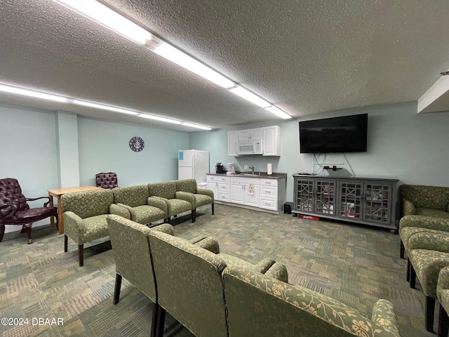 living room featuring a textured ceiling, sink, and carpet flooring