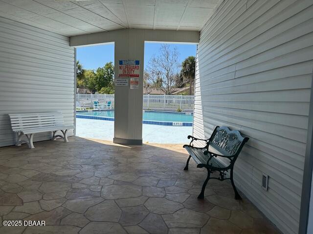 view of patio with a community pool and fence