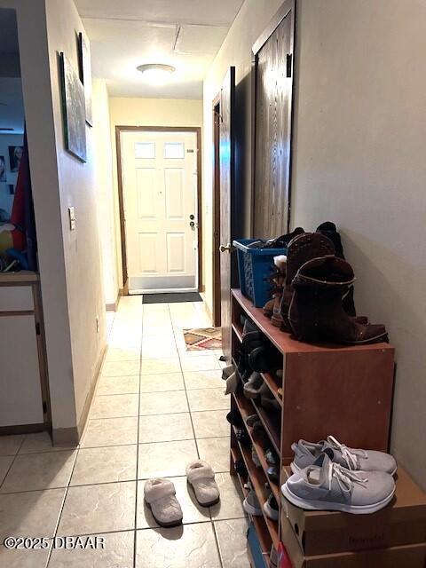 doorway featuring light tile patterned floors and baseboards