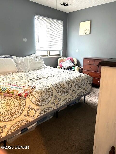 carpeted bedroom featuring visible vents and a textured ceiling