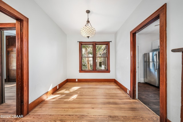 unfurnished dining area with light wood-type flooring and an inviting chandelier