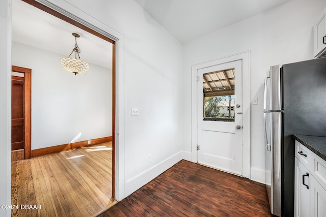 kitchen featuring white cabinets, stainless steel fridge, decorative light fixtures, and dark hardwood / wood-style floors