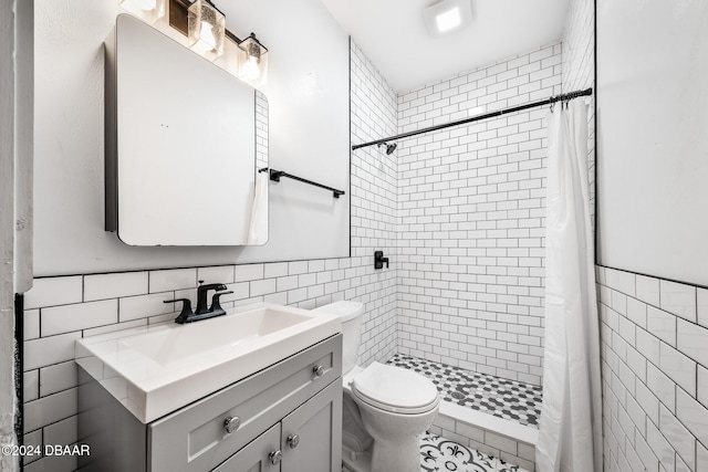 bathroom with curtained shower, vanity, tile walls, and toilet