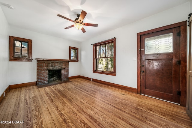 unfurnished living room featuring a fireplace, hardwood / wood-style flooring, and ceiling fan