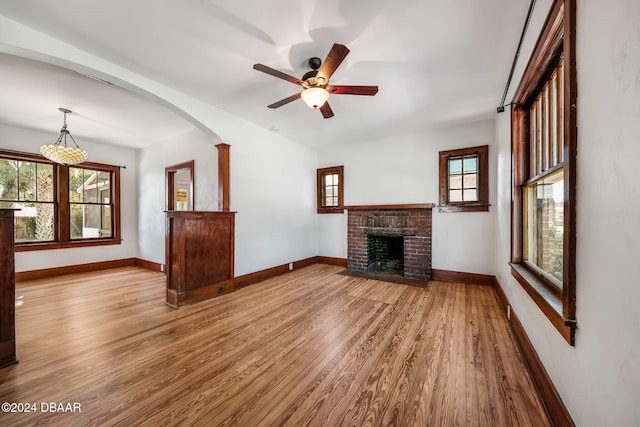 unfurnished living room with decorative columns, ceiling fan, a fireplace, and light hardwood / wood-style floors