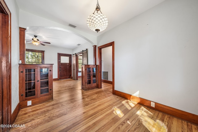 interior space with hardwood / wood-style flooring, ceiling fan, and a barn door