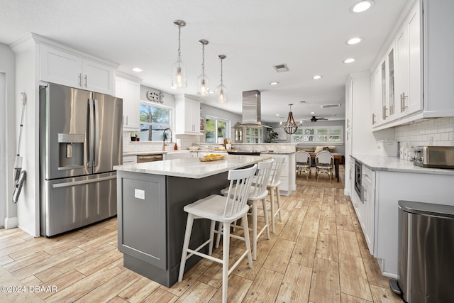 kitchen featuring white cabinetry, stainless steel appliances, light hardwood / wood-style floors, and decorative light fixtures